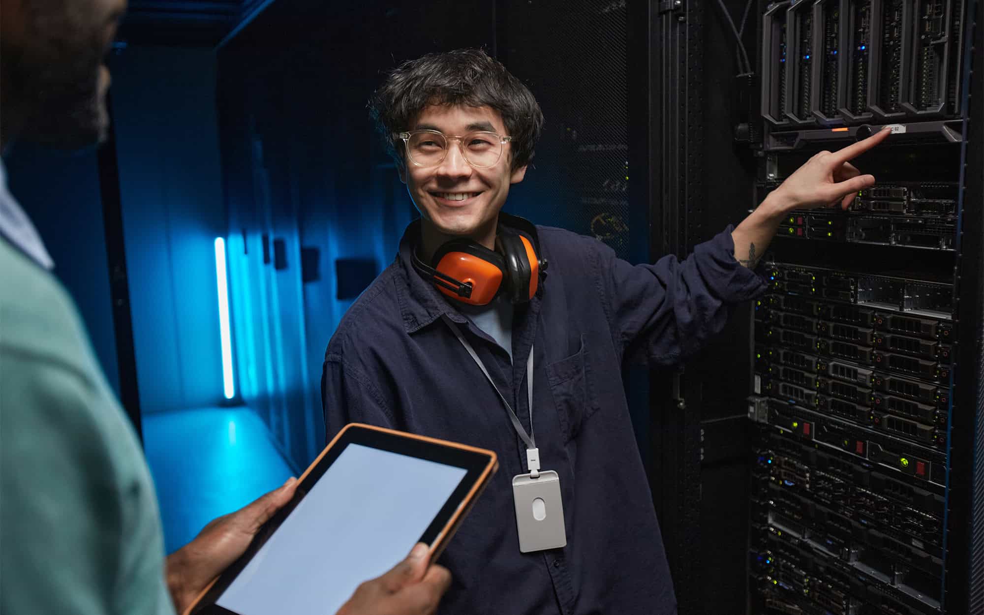 Server Admin Smiling at Colleague Pointing to a Server