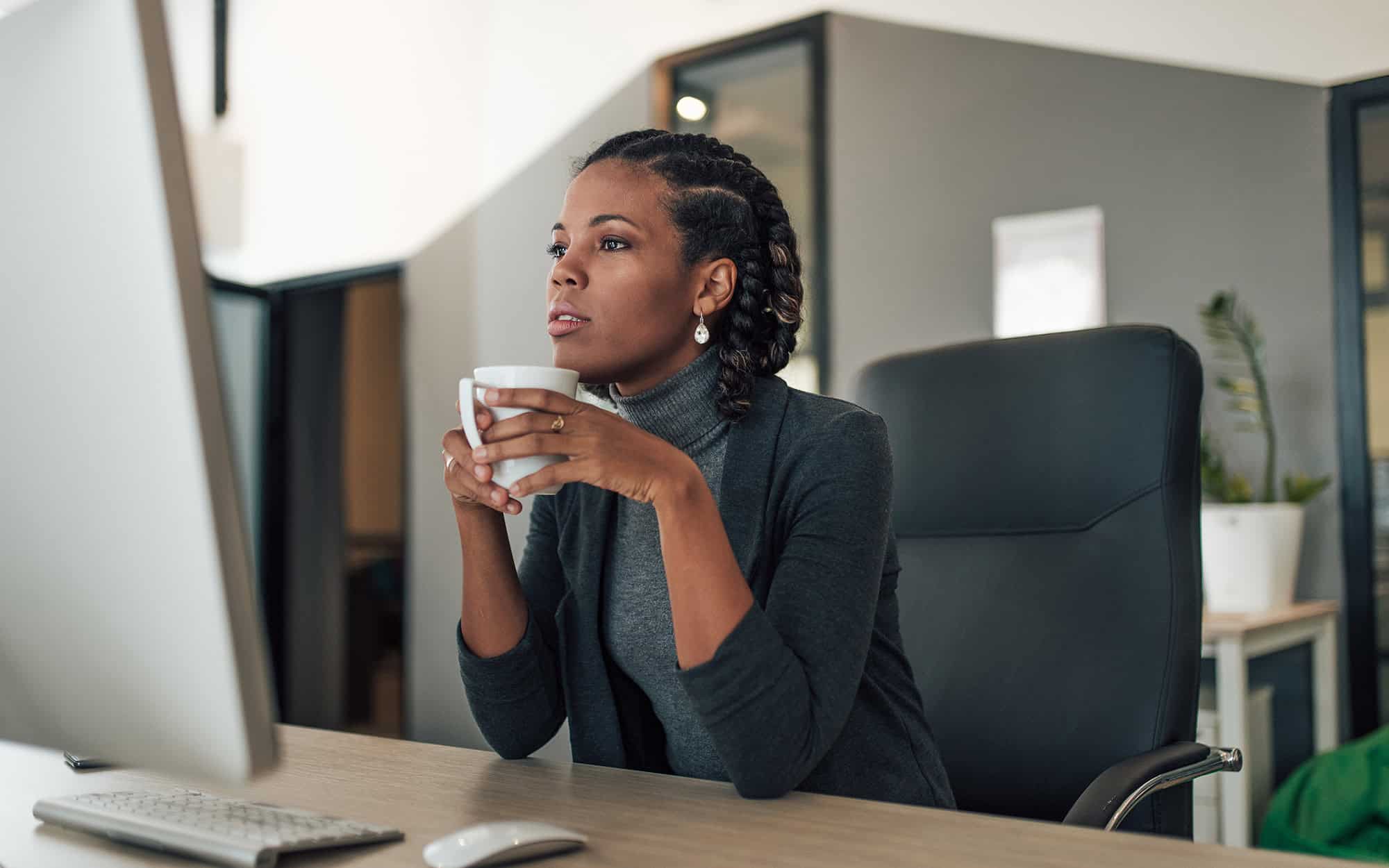Woman Drinking Coffee and Looking at Google Workspace on Monitor