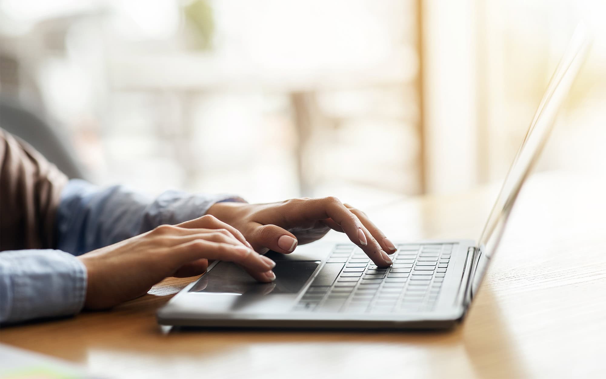 Female hands typing on laptop over blurred background