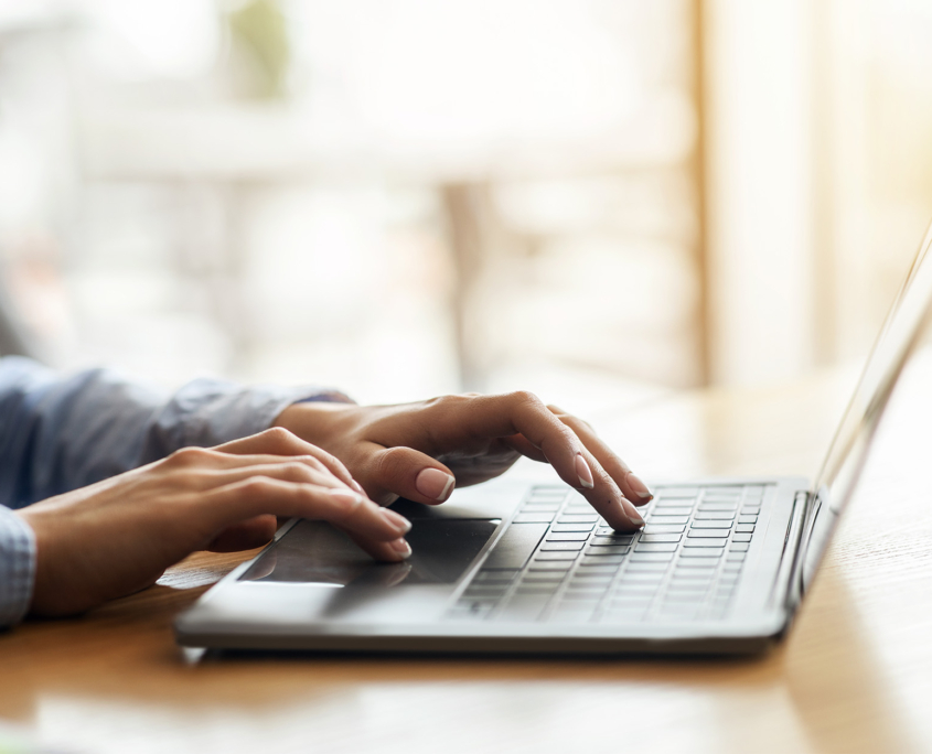 Female hands typing on laptop over blurred background