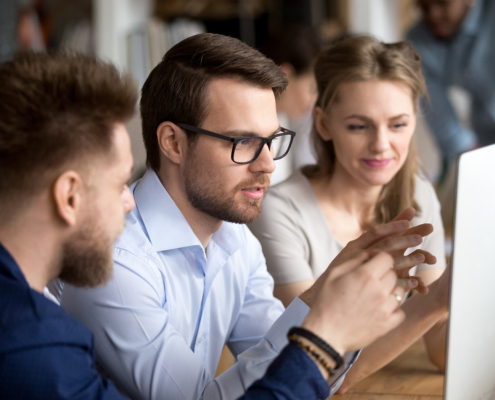 Serious employees working together discussing computer task in office