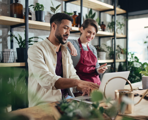 Shop assistants with laptop working in potted plant store, small business concept