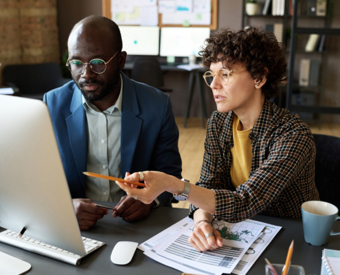 Two workers in office looking at information on computer