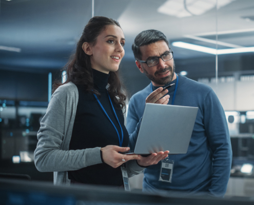Portrait of Two Happy Female and Male Engineers Using Laptop Computer