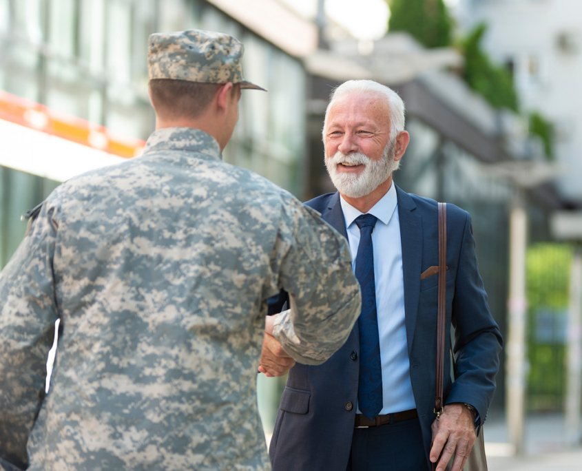 Senior businessman shaking hands with soilder outdoor